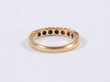 a close up of a gold ring with red and black stones