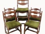 four wooden chairs with green cushions sit in a row