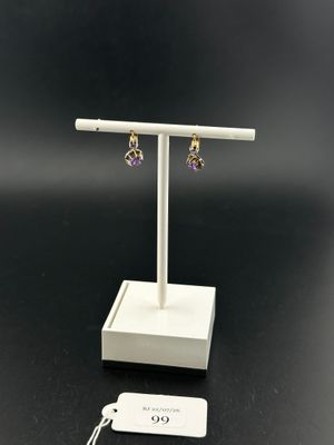 a pair of earrings on a white stand with a tag