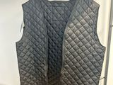 un gilet matelassé noir suspendu à un portant dans un magasin de vêtements