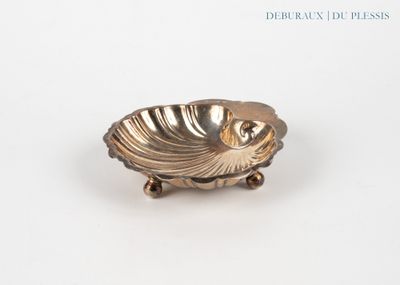 une assiette en argent ornée d'un coquillage, posée sur un fond blanc