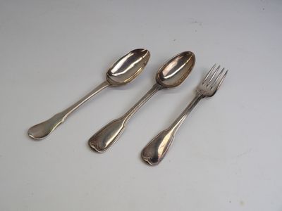 trois cuillères et une fourchette en argent sur une surface blanche