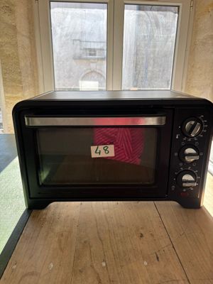 un micro-ondes noir posé sur une table en bois devant une fenêtre