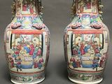 pair of chinese vases sitting on a gray surface with a black background