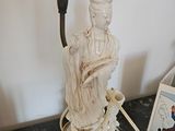 une statue représentant une femme tenant une bougie posée sur une table