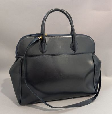 Le sac à main en cuir noir est posé sur une surface blanche.