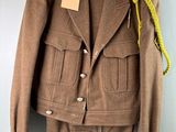 une veste marron accrochée à un mur, avec une étiquette dessus