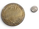 a small coin next to a smaller coin on a white surface