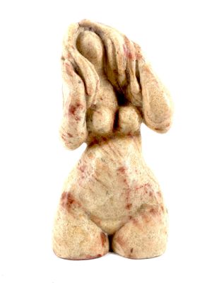 une petite statue représentant un chien assis sur une surface blanche
