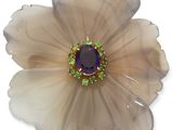 broche en forme de fleur ornée de pierres violettes et vertes sur fond blanc