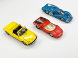 trois petites voitures posées sur une surface blanche