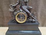 une statue représentant un homme assis sur une horloge, tenant une clé