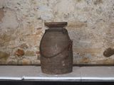 un grand vase marron posé sur une table devant un mur de pierre