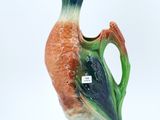 a small vase with a bird on it on a white surface