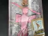 barbie doll in a pink dress in a box on a black surface