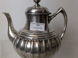 a silver tea pot sitting on a glass table