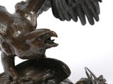 bronze statue of a bird on a rock with its wings spread