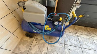 un compresseur d'air bleu posé sur un sol carrelé