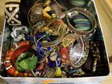 a metal container filled with assorted jewelry on a table