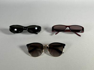 three pairs of sunglasses sitting on top of a white surface