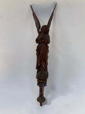une image représentant une statue d'ange posée sur un poteau en bois