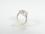 a close up of a ring with a pink stone on a white surface