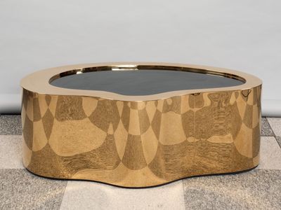 un gros plan sur une table basse dorée posée sur un sol à carreaux