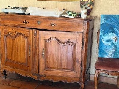 un tableau accroché au mur, à côté d'un meuble et d'une chaise