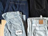 several pairs of jeans are stacked on top of a cardboard box