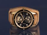 a gold watch with a black face on a black surface