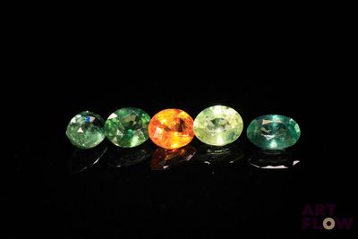 a group of five different colored gems sitting on top of a black surface