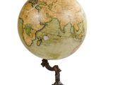 un globe antique posé sur un trépied, avec un fond blanc