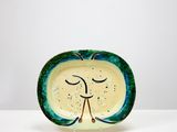 une assiette verte et blanche sur laquelle est peint un visage