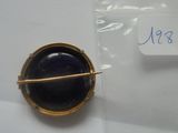 une photo d'une broche en or sertie d'une pierre bleue