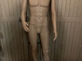 a mannequin in a bathroom with a toilet in the background