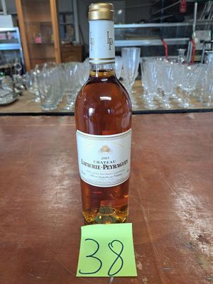 une bouteille de vin posée sur une table, avec des verres en arrière-plan