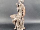 statue of a woman sitting on a rock holding a dog