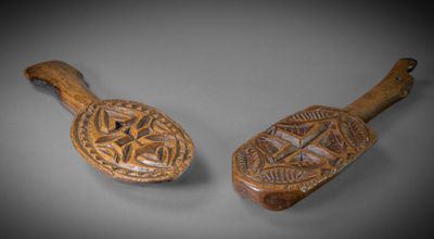 two wooden spoons with designs on them sitting on a table