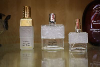 trois flacons de parfum posés sur une table à côté d'un flacon de parfum