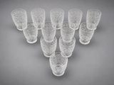 six clear glasses are arranged in a triangle on a gray background