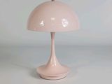 une lampe rose posée sur une table blanche