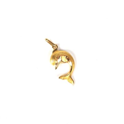 a close up of a gold dolphin pendant on a white background
