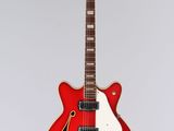 a red electric guitar hanging from a string on a white wall