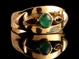 un gros plan d'une bague en or sertie de pierres vertes et rouges