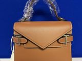 un sac à main en cuir beige muni d'une poignée en plastique transparent, posé sur une table