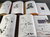 several open books with drawings of people on them sitting on a table