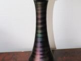 a black vase sitting on a table with a white wall in the background