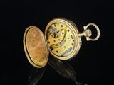 a gold pocket watch sitting on a black surface