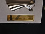a silver plate with a bird on it in a box