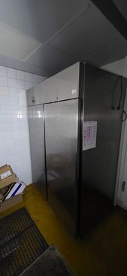 a silver refrigerator in the corner of a room with a box on the floor